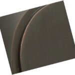 Close-up of a round, dark metallic object with a curved edge and a subtle seam, positioned at an angle against a plain white background.