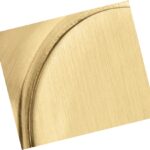 Close-up of a brushed brass or gold-colored metal surface, showing a curved edge and fine texture. The image is slightly rotated, giving a diagonal perspective.