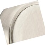 Close-up of a brushed metal surface, possibly part of a rounded object or appliance, shown at an angle. The texture and slight curve are visible, but the exact object is not clearly identifiable.