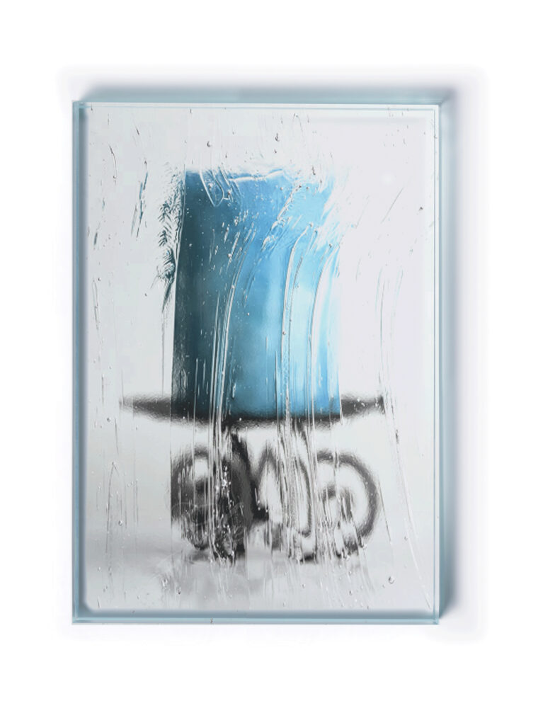 A blue candle on an ornate black metal holder with curled details set behind privacy glass.