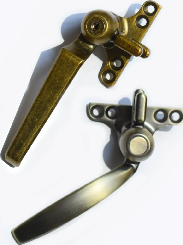 Two vintage-style window handles with multiple holes in their mounting plates, positioned on a white background. The handles are metallic, one darker and one lighter in color, with a slightly aged appearance.